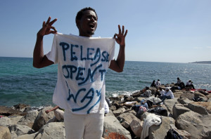 A migrant shouts a slogan as he wears a Tee Shirt with the message, "Open The Way" as he stands on the seawall at the Saint Ludovic border crossing on the Mediterranean Sea between Vintimille, Italy and Menton, France